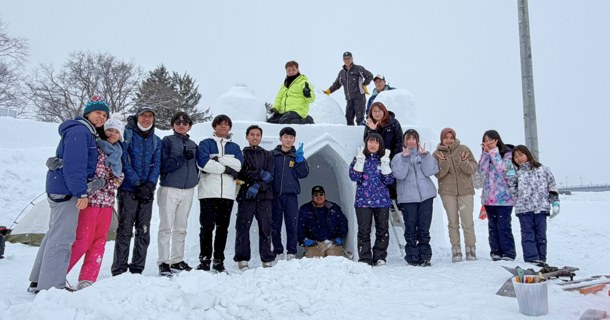 Snow mosque team in a diverse background, from children to adults, work together craving a huge ice block into a mosque. 